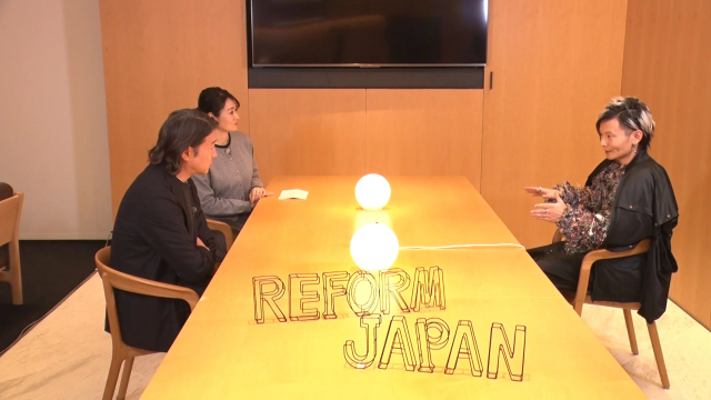 REFORM JAPANの文字と照明が置かれたテーブルを囲んで対話する男女