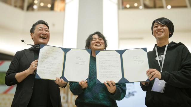 協定書を掲げる3人の男性