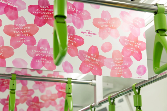 電車の中吊り広告で、子供たちの夢が桜の花びらと共に紹介されている