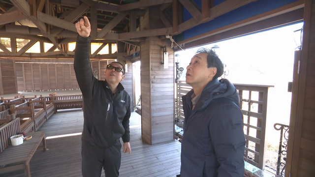 木造建築で説明する男性たち